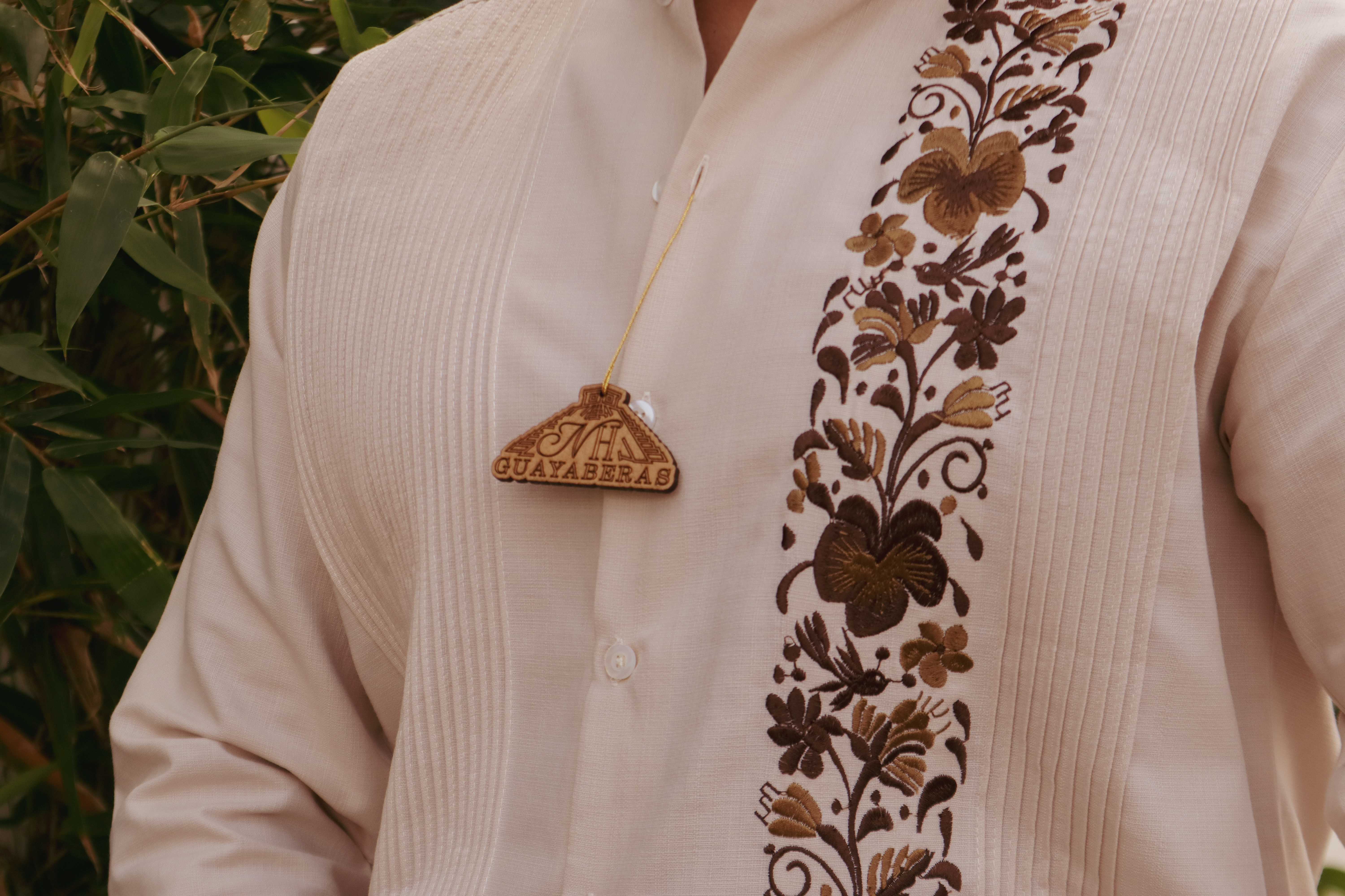 A person wearing a guayabera in a beautiful Yucatecan landscape with ancient ruins in the background.